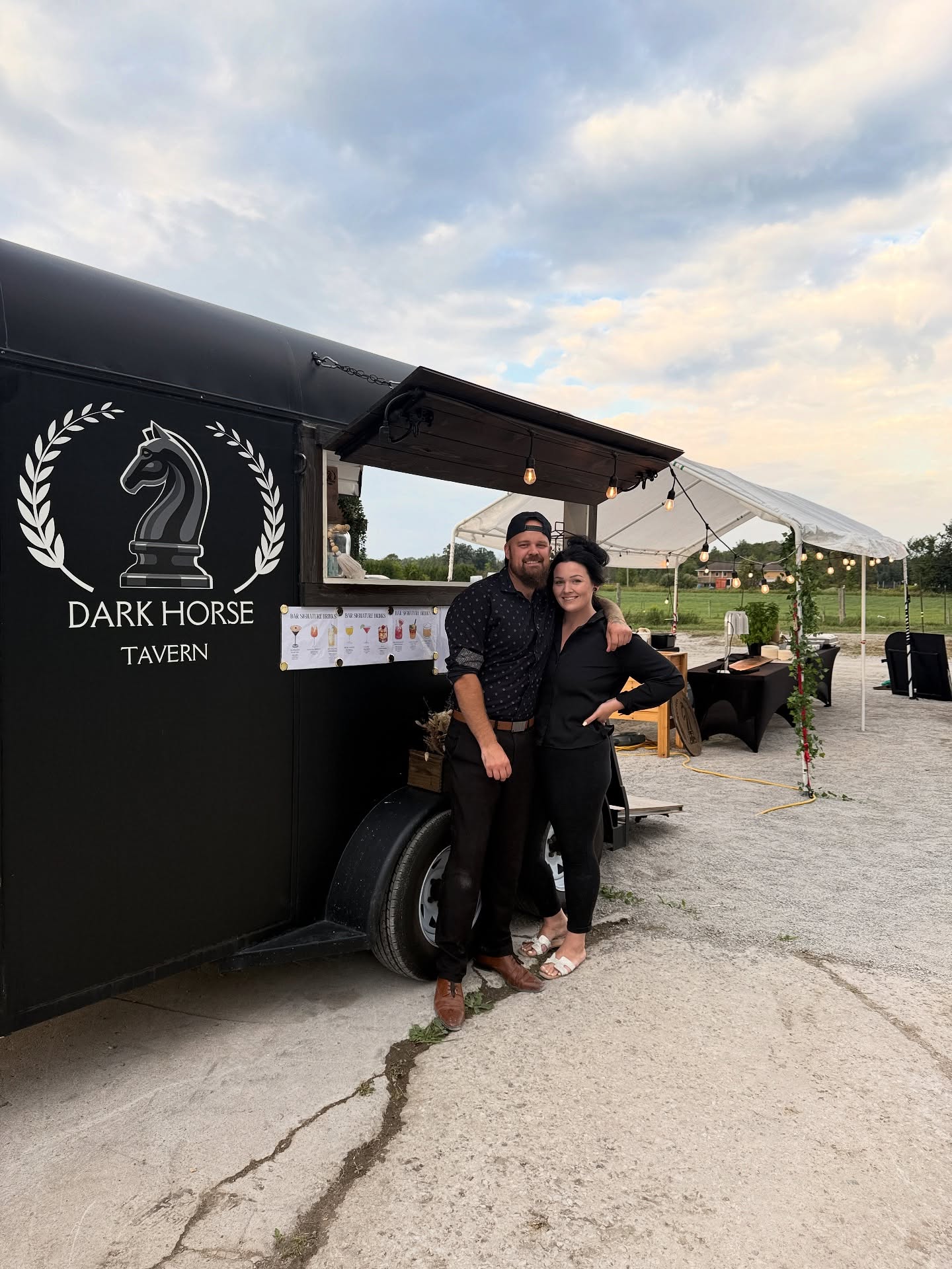 Matt and Gracie standing together in front of the Dark Horse Tavern trailer